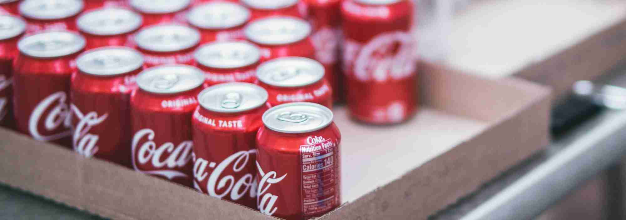 Pack of Coca-Cola cans in a cardboard box, refreshing soft drinks for any occasion.