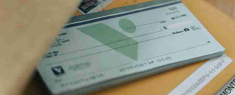 Person reviewing a check and financial documents for salary comparison.