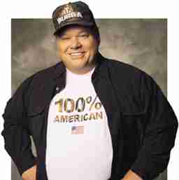 Person wearing "100% American" t-shirt and cap, smiling confidently.