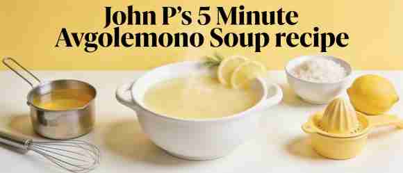 Bowl of Avgolemono soup with lemon slices and ingredients on a kitchen counter.