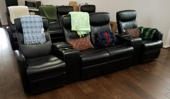 Black leather 4-seat home theater recliner with built-in storage consoles for added convenience and.