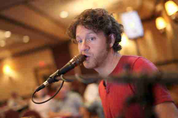 A man singing into a microphone during a live music event.