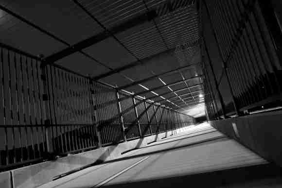 Bridge walkway with modern metal railings and overhead structure.