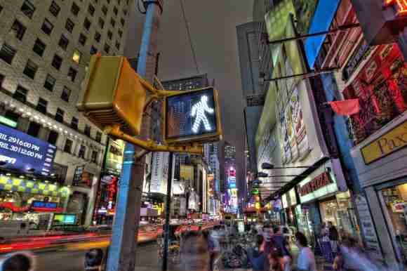 Bright Times Square at night with illuminated billboards and busy pedestrians.